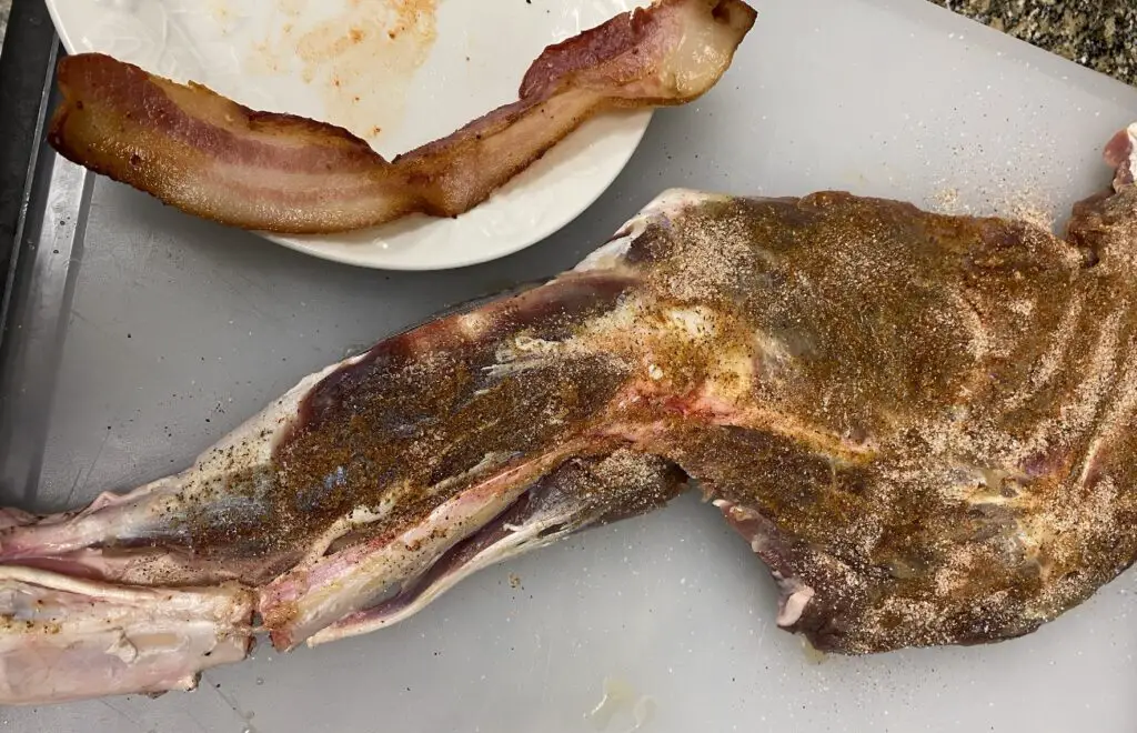 Rubbing whole deer leg with bacon fat